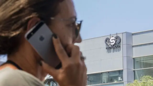 ইসরায়েলের হার্জলিয়ায় এনএসও গ্রুপের অফিসের সামনে ফোন হাতে এক নারী।