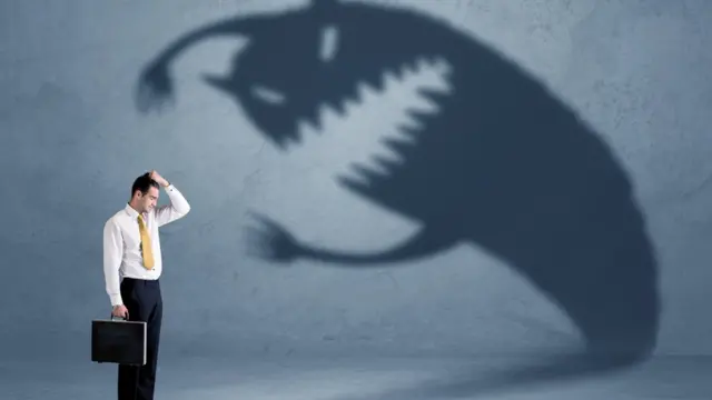 Hombre delante de la sombra de un monstruo.