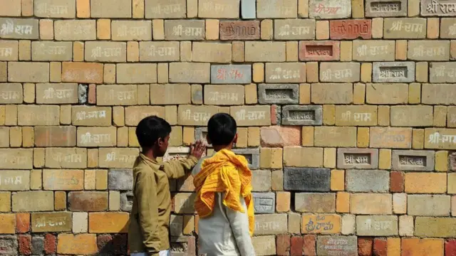 ઈંટની દિવાલ પાસે ઉભેલાં બે બાળકો