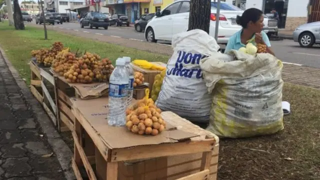 Mulher vende frutas no farol