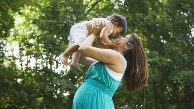 Una mujer alza a un niño en brazos