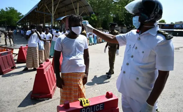 පිරිසක් නිරෝධායන මධ්‍යස්තානයකට රැගෙන යාමට පෙර උෂ්ණත්වය මනිමින්