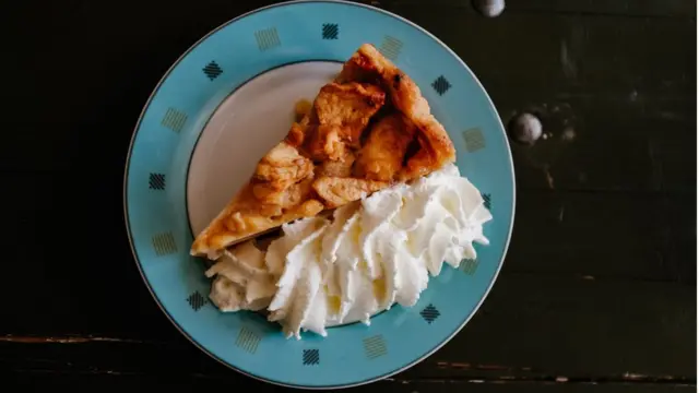 Кусок яблочного пирога со взбитыми сливками.