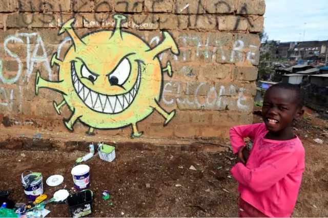 A child stands next to a cartoon depiction of Covid-19.