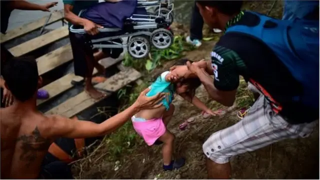 মেক্সিকোর একটি নদী থেকে অভিবাসী একটি দলের সঙ্গে থাকা একটি শিশুকে উদ্ধার করা হচ্ছে