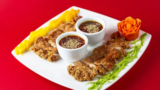 Plato de comida chino / peruana con carne y una salsa dulce en el medio.