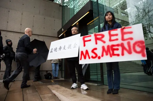 Robert Long (L) and Ada Yu hold signs in favor of Huawei Technologies Chief Financial Officer Meng Wanzhou outside her bail hearing at British Columbia Superior Courts following her December 1 arrest in Canada for extradition to the US, in Vancouver, British Columbia on December 11, 2018. (Photo by Jason Redmond / AFP)JASON REDMOND/AFP/Getty Images