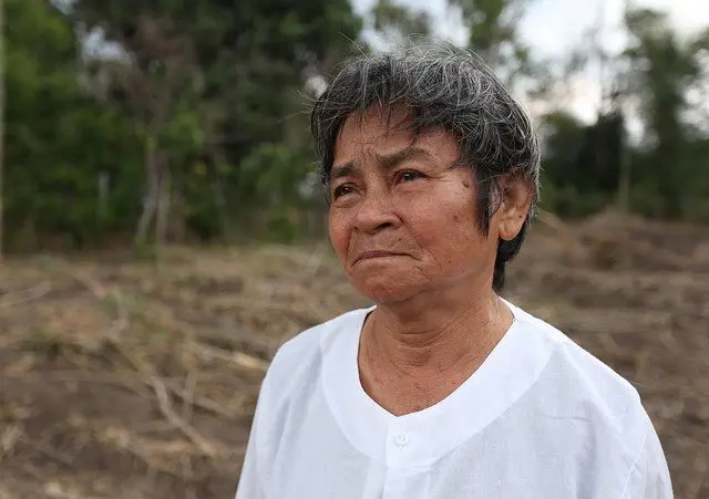 นางหล่า ทวีทรัพย์ ยืนอยู่บนที่ดินของตนที่เอาไว้ปลูกผัก