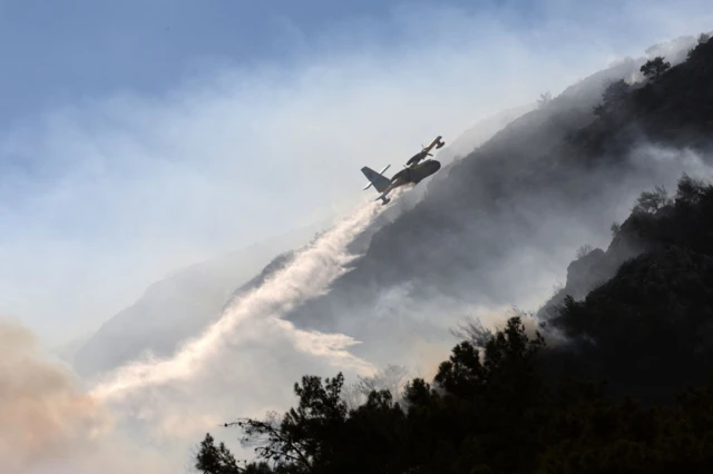 طائرة إطفاء تسقط المياه على حريق غابات شب في منطقة داتشا بمدينة مولا بتركيا