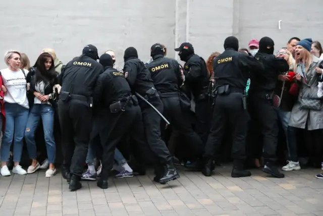 Riot police grab people in order to detain them, from a crowd of women on 8 September