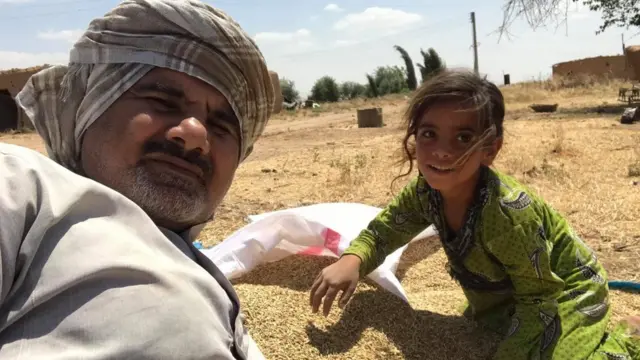 Abood Hamam and a girl with some harvested barley
