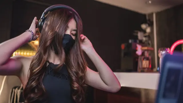 마스크를 착용하고 클럽 DJ 일을 하고 있는 여성