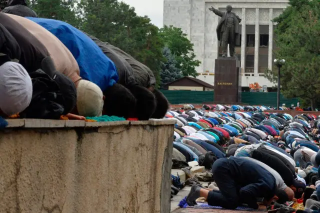Kyrgyz Muslims pray in central Bishkek, with a monument of Soviet State founder Vladimir Lenin seen in the background, 25 June