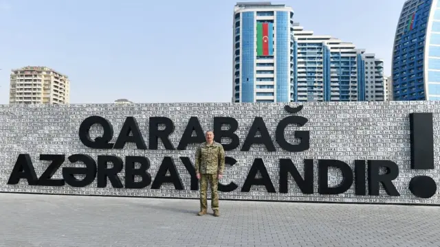 Алиев на фоне стены из номеров автомобилей и надписи "Карабах - это Азербайджан!"