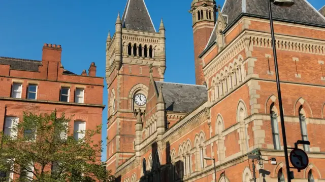 Червоноцегляна будівля з годинниковою вежею у неоготичному стилі