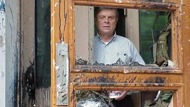 Ambassador James Sasser looks through the broken doors of the a US embassy building in Beijing