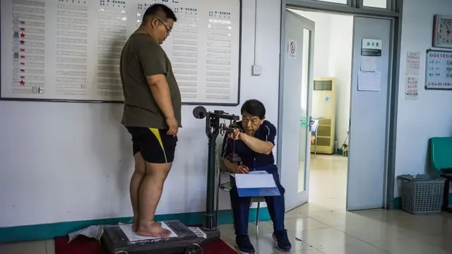 એક વ્યકિતવજન કરી રહી છે તેની તસવીર