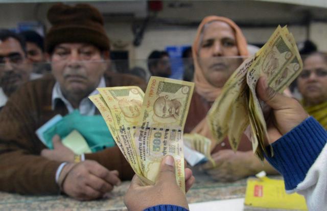 An Indian bank teller counts old notes