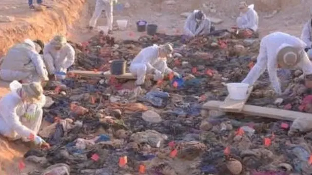 एक गड्ढे से शवों को निकालने का काम चल रहा है.