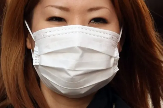 A woman wearing a mask walks past about the outbreak of coronavirus in Wuhan, China at Ginza shopping district in Tokyo, Japan, January 26, 2020. (Photo by Hitoshi Yamada/NurPhoto via Getty Images)