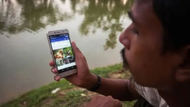 Мешканець країни сидить з телефоном біля озера