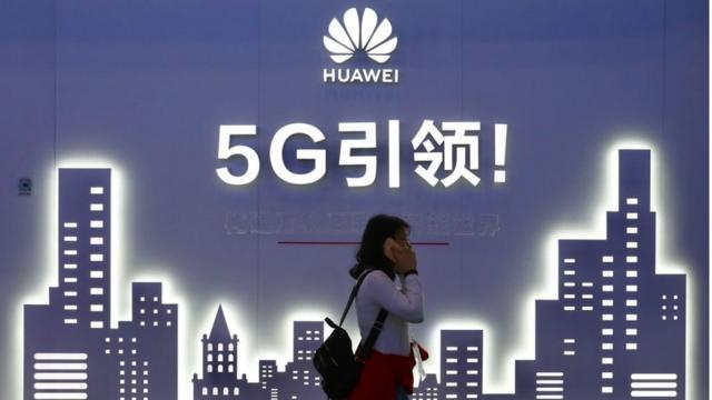 A woman walks past Huawei 5G sign at the PT Expo China 2019 at the China National Convention Center in Beijing, 31 October 2019