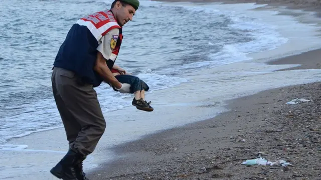 Спасатель несет тело Айлана Курди