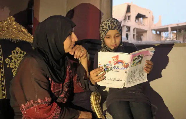 Islam leyéndole un libro a su madre.