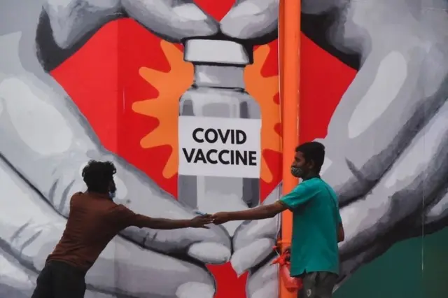 indian workers give final touches to a huge mural made on a wall outside the Tambaram railway station to promote awareness on the Covid-19 coronavirus disease vaccination in Chennai, India, 04 July 2021