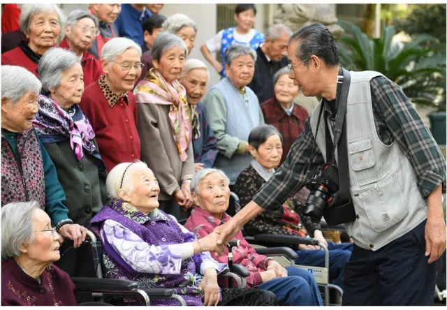 86歲的老年攝影愛好者謝金聲為湖州社區裏老年公寓的老人拍合影