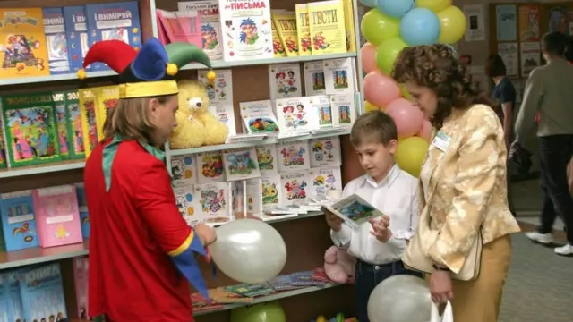 Хлопчик біля стенда із підручниками і навчальними книгами