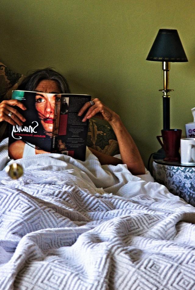 Una mujer lee en cama.