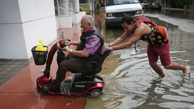 Un joven empuja la silla de ruedas eléctrica de un hombre mayor.