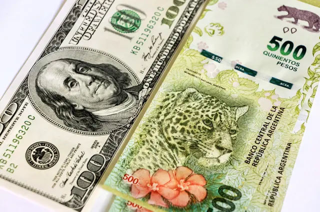 Billete de 100 dólares y de 500 pesos