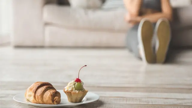 Un croissant y un cupcake con una mujer en el fondo