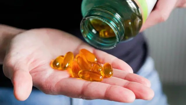 Cápsulas de vitamina D na mão de uma pessoa