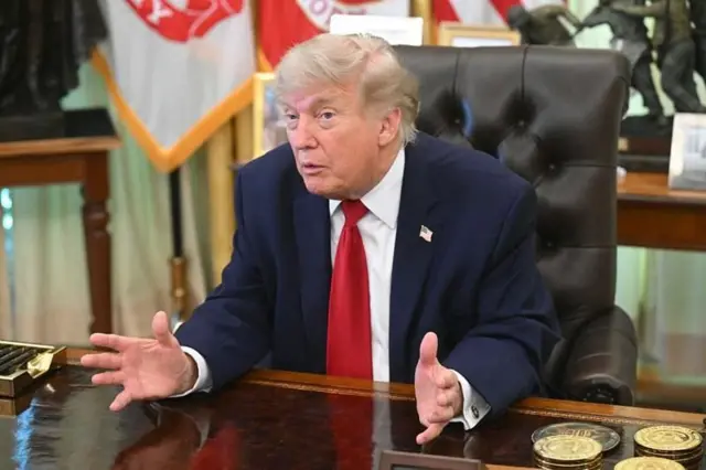 Donald Trump sentado atrás da mesa no Salão Oval
