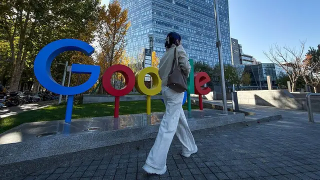 Офис Google, на фоне логотипа компании идет девушка в синих джинсах с сумкой. На фоне виден стеклянный небоскреб