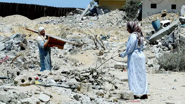 Mulheres palestinas tentam recuperar objetos em meio os escombros de casas no bairro Brasil de Rafah, em 23 de maio de 2004