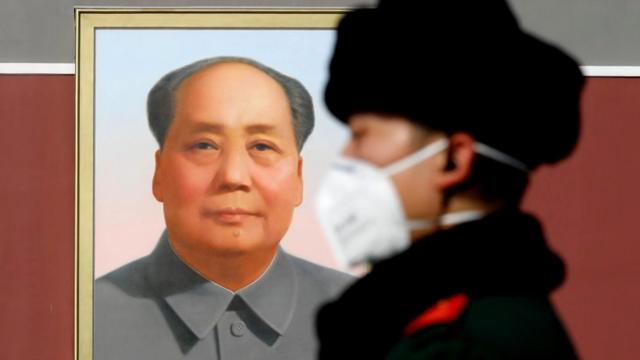 Mao portrait and policeman wearing a face mask