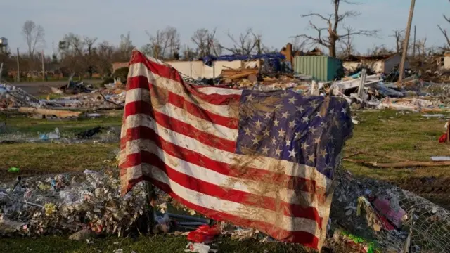 A muddied American flag is seen draped over wreckage in Rolling Fork, Mississippi