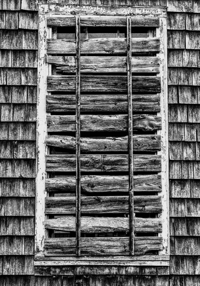 A black and white image of wood nailed across a window