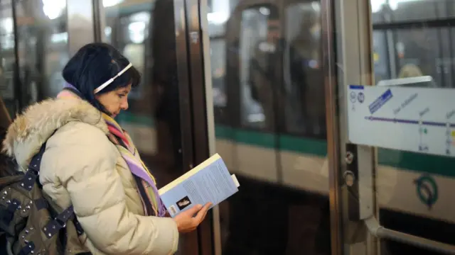 سيدة تقرأ في كتاب وهي تقف على رصيف القطار