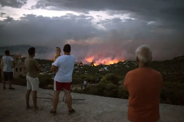 People watch a wildfire in the town of Rafina, near Athens.