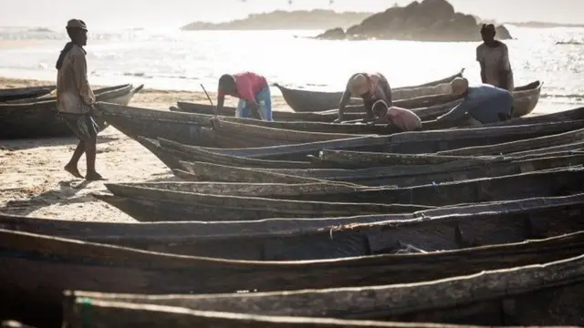 Mendaratkan pirogue ke pantai saat matahari terbit.