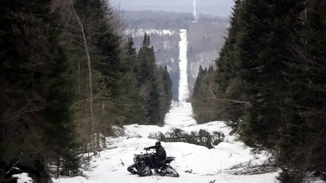 Un policía patrulla la frontera en un paisaje nevado.