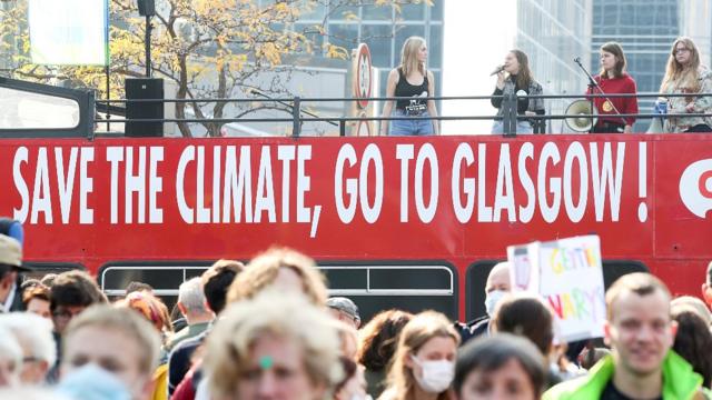 Jóvenes en un autobús con un cartel que dice "salvar el clima, ir a Glasgow"