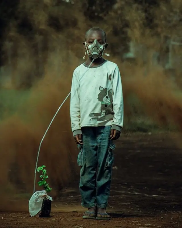 টবের একটি গাছের সাথে বাঁধা অক্সিজেন মুখোশ পরা এক কিশোর