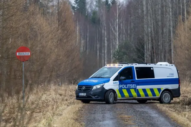 Эстонская полицейская машина стоит поперек лесной дороги