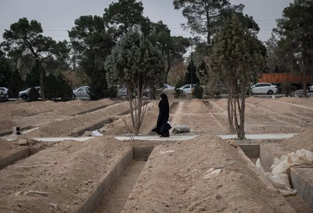 कबरींजवळून चालत जाणारी एक महिला